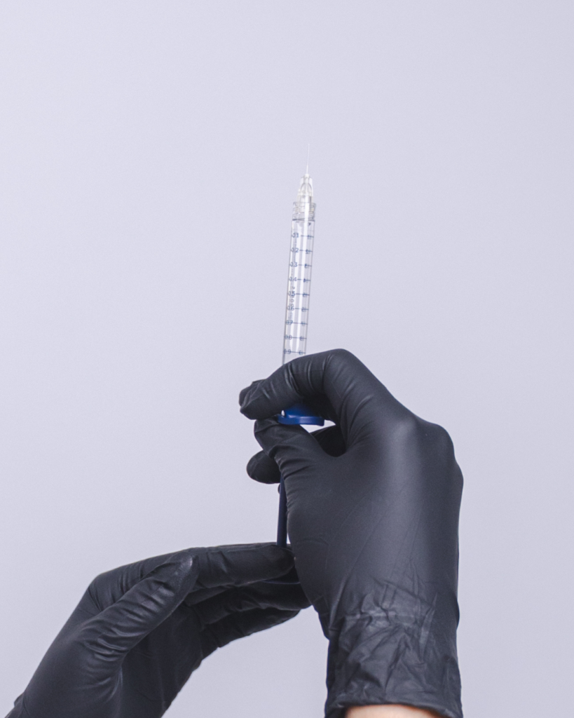 Provider wearing black gloves preparing an injectable treatment for facial rejuvenation to restore volume lost from Ozempic face and rapid weight loss.