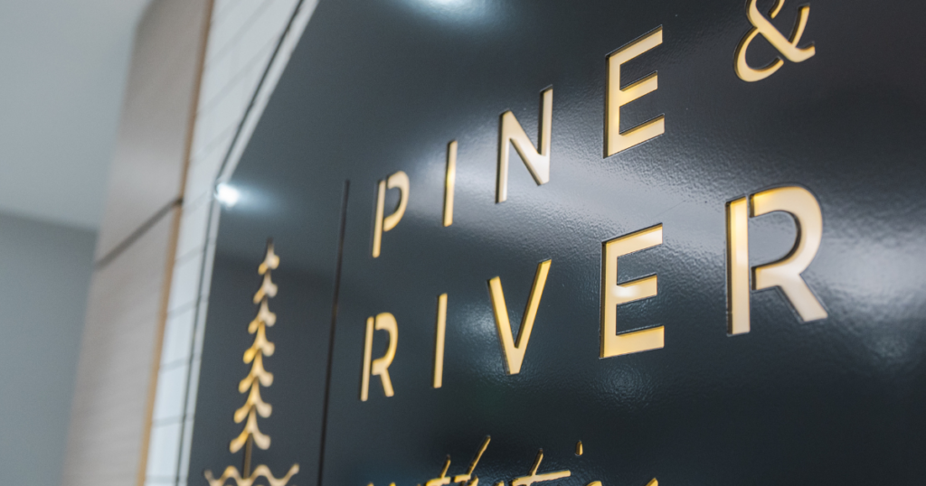 Gold Pine & River Aesthetics logo displayed on a dark wall inside the clinic.